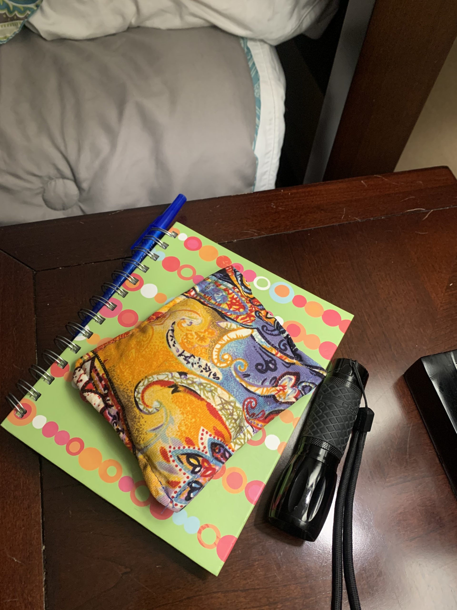 A bedside table holding a dream journal, dream pillow, a pen, and a flashlight